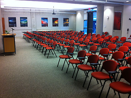 Chairs arranged in an auditorium facing a lecturn.