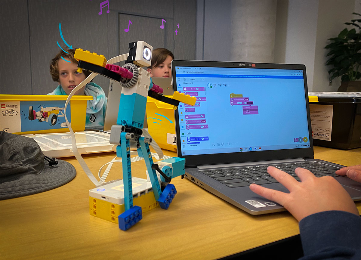 Students program a dancing LEGO robot using a laptop computer