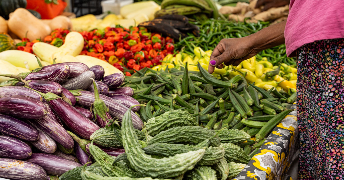 A woman selects from a colorful array of vegetables at an outdoor market.