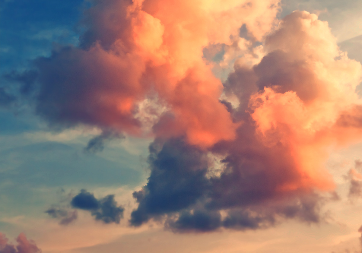 A blue sky with clouds illuminated in vibrant sunrise colors.